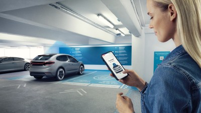 A young woman controls functions of her parking car via her smartphone.